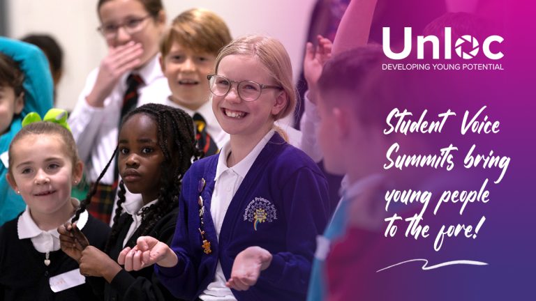 A group of smiling schoolchildren sit together at an event, with the Unloc logo and the words Student Voice Summits bring young people to the fore! displayed beside them.