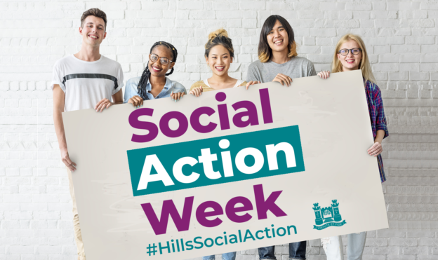 Five young adults stand against a white brick wall, holding a large sign reading Social Action Week #HillsSocialAction with a blue emblem on the bottom right-hand side.
