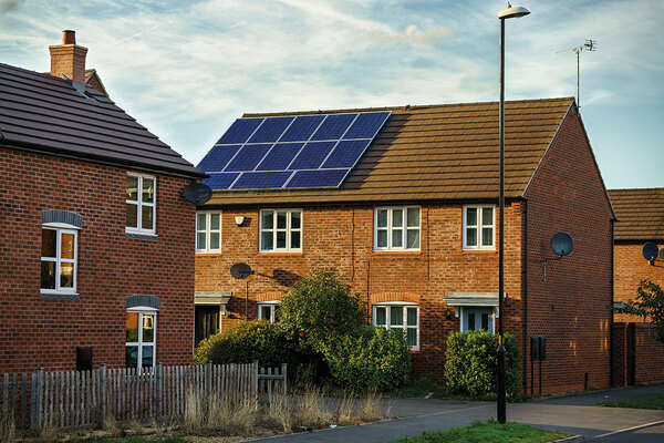 A solar panel on the roof of a brick house.