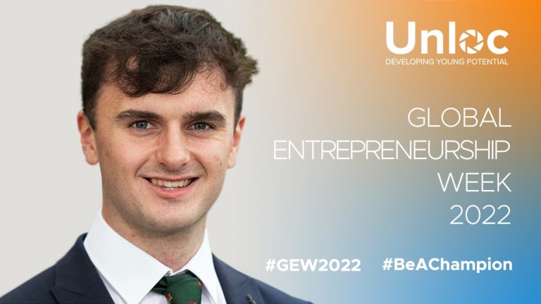 A young man in a suit and tie smiles in front of a gradient background with Unloc Global Entrepreneurship Week 2022 and hashtags #GEW2022 and #BeAChampion.