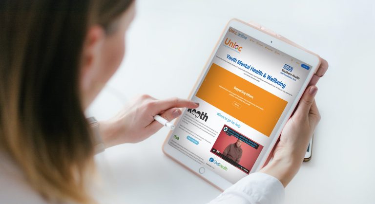 A person uses a stylus to browse a youth mental health and wellbeing website on a tablet.